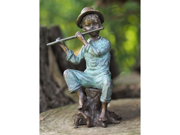 Skulptur aus Bronze sitzender Junge auf einem Baumstamm beim Flöte spielen