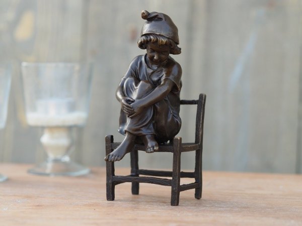 Nachdenkliches Mädchen auf einem Stuhl aus Bronze