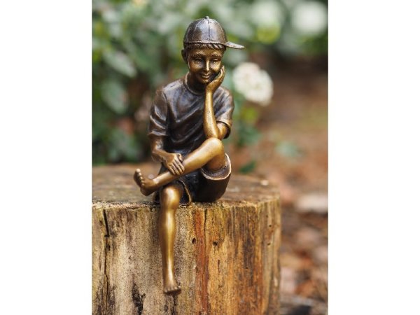 Bronzefigur sitzender Junge mit Basecap