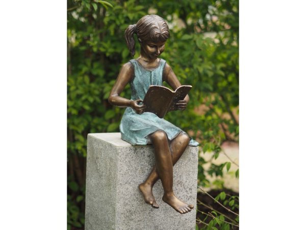 Skulptur aus Bronze sitzendes Mädchen mit Zöpfen beim Buch lesen
