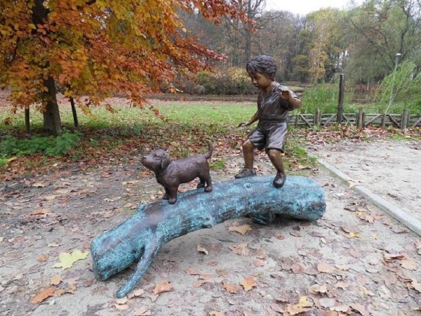 Bronzefigur balancierender Junge mit seinem Hund auf einem Baumstamm