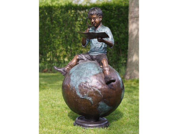 Figur aus Bronze sitzender Junge auf einem Globus mit Karte und Lupe in der Hand