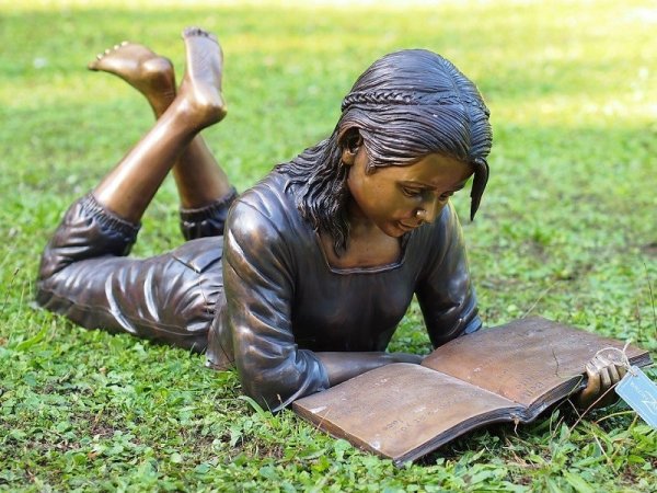 Figur aus Bronze liegendes Mädchen mit überkreuzten Beinen beim Lesen